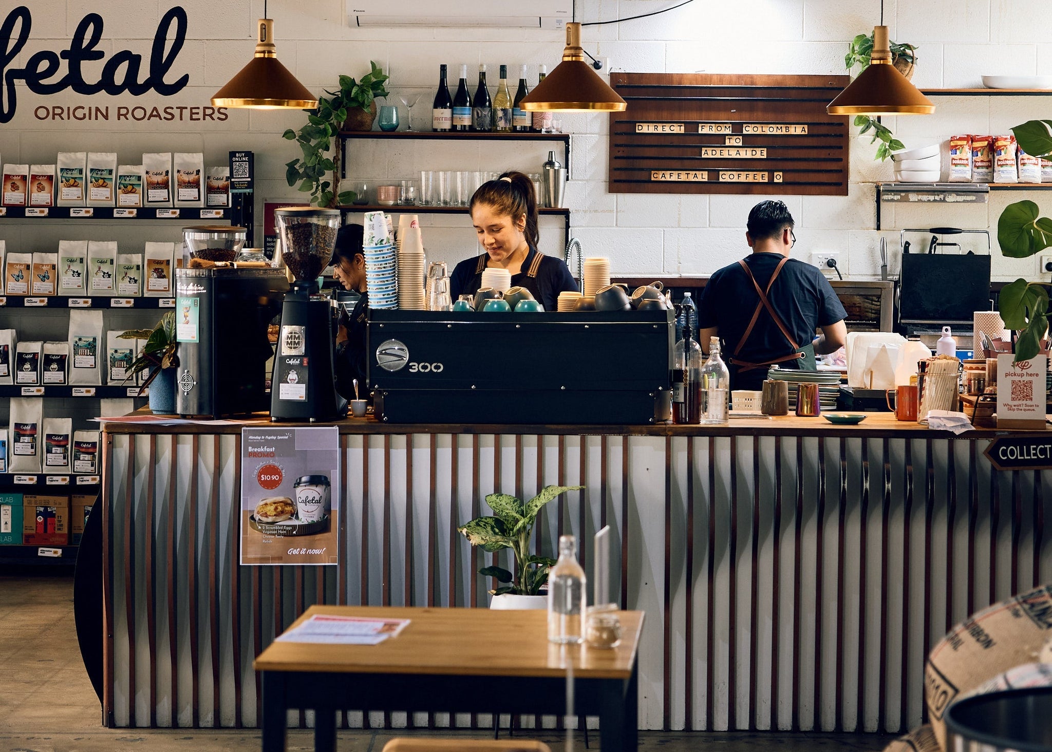 Interior of Cafetal coffee shop with customers at the counter and tables in the foreground.